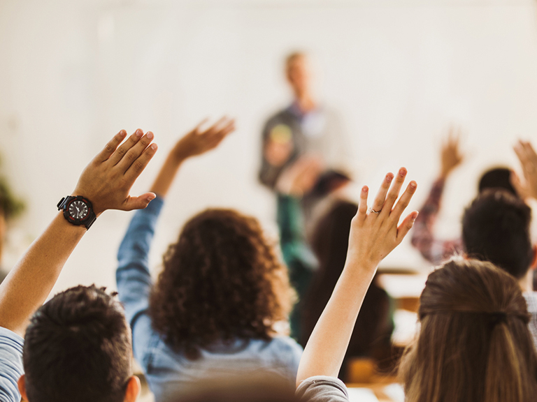 People raising their hands at a lecture.